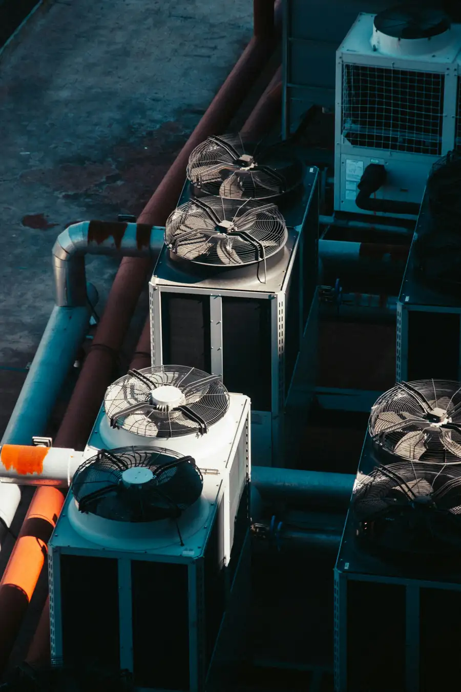 Several outdoor air conditioning units with fans and copper piping, seen from above