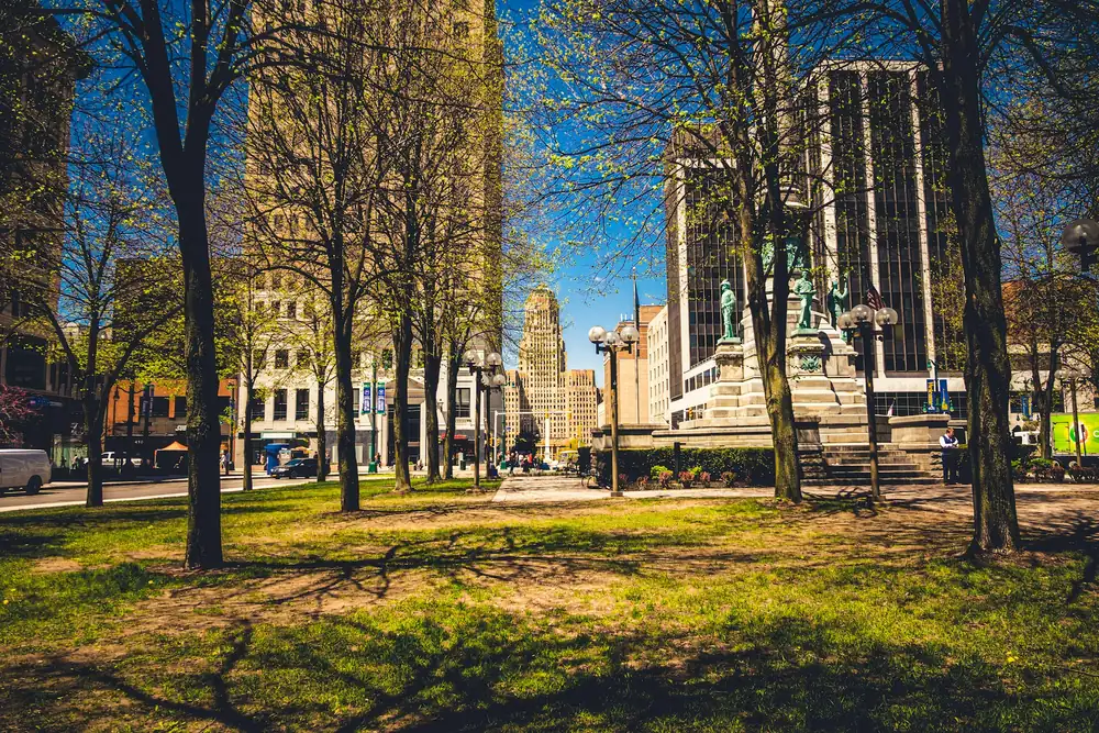 Trees and lawn in a downtown Buffalo square with City Hall and office towers behind